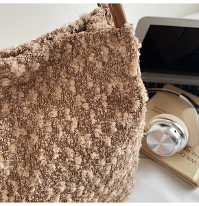 Detailaufnahme der beigen Wolltextur und des braunen Ledergriffs an der Bucket Bag