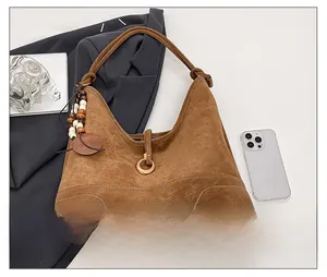 Detail of brown suede hobo bag featuring a wooden bead pendant and metal buckle closure
