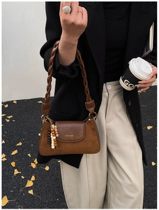 Detail of dark brown suede shoulder bag with braided strap and colorful bead accents