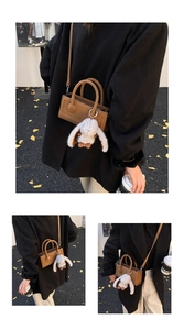 Detail of a brown vintage baguette bag with a plush bunny charm and magnetic buckle