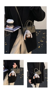 Detailed view of dark green suede square handbag with cute plush bunny charm and strap