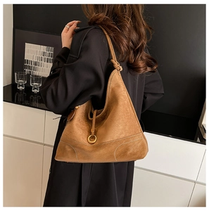 Close-up of brown suede hobo bag with contrast stitching and golden hardware details