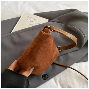 Detailaufnahme der braunen Wildledertasche auf einem schicken grauen Blazer-Hintergrund