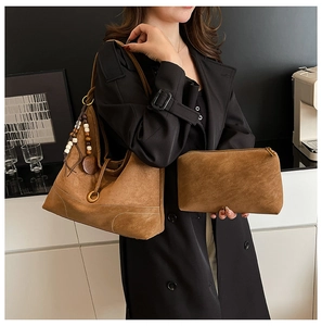 Brown suede tote bag with ethnic beaded charms shown on model wearing black coat