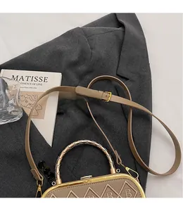 Detail of khaki leather handbag featuring B-letter embroidery and gold woven metal handle