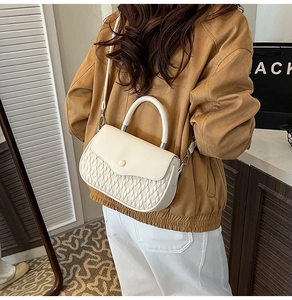 Detail of cream white quilted crossbody bag with top handle and round buckle decor