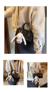 Detail of minimalist black baguette bag featuring cute white rabbit plush keychain