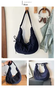 Detail of navy blue polka dot hobo bag with drawstring pleats and side ribbon bow