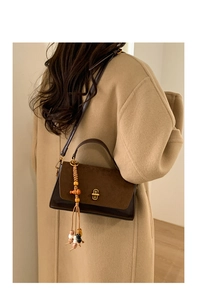 Detail of retro brown crossbody bag with matte texture and decorative beaded tassel