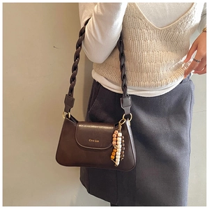 Detail of dark brown leather handbag with woven strap and decorative beaded tassels