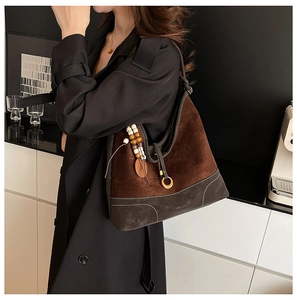 Detail of dark brown suede and leather shoulder bag with white contrast stitching