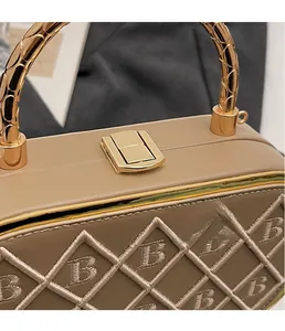 Macro detail of gold snake-pattern handle and hardware lock on beige crossbody bag