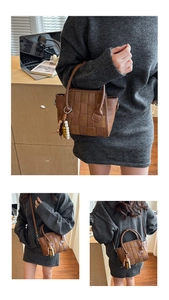 Detail of woven brown leather handbag with checkered suede texture and beaded charm