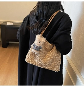 Detailansicht der cremefarbenen Lammwoll-Tasche mit Lederriemen und Bärenanhänger