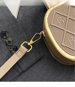 Detailed view of beige leather bag featuring B-letter embroidery and gold metal hooks