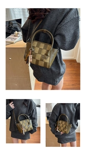 Detailed macro view of dark green woven leather texture and bead tassel of the handbag