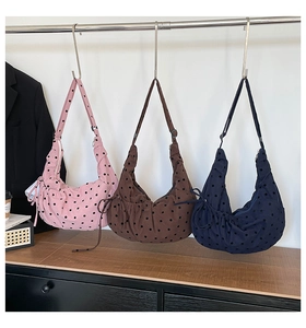 Detailed view of polka dot crescent tote bags in pink, brown, and navy with pleated base