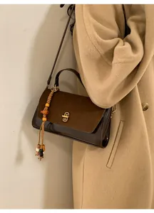 Detail of vintage suede crossbody bag with colorful wooden beads and golden lock