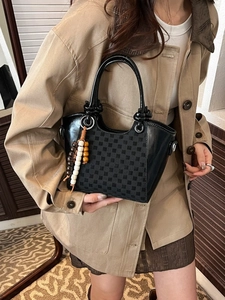 Schicke karierte Eimertasche mit Holzperlenanhänger und Knotengriff an Model