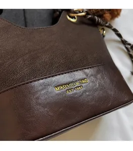 Detailed close-up of dark brown handbag showing suede and smooth leather textures
