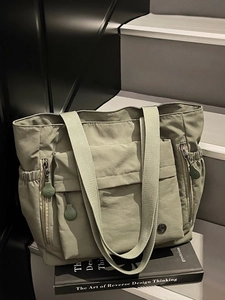 Sage green nylon tote bag with multiple pockets and drawstring side on stairs