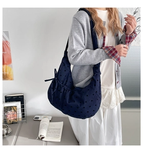 Detail of navy polka dot tote bag with a decorative side bow for casual styling