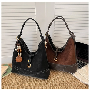 Detail of suede hobo bags with woven handles and wooden bead tassels on jute rug