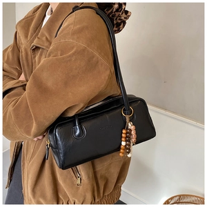 Detail of black rectangular shoulder bag with signature tricolor wooden bead charm
