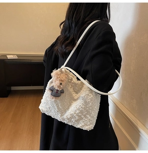 Detail der weißen Woll-Beuteltasche mit Lederriemen und niedlichem Bären-Anhänger