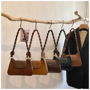 Detail showing various colors of women's shoulder bags with woven straps on a wooden hanger