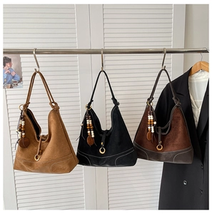 Three suede tote bags in camel, black, and dark brown with stitching and wooden beads