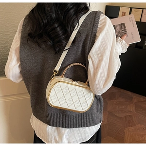 Detail of white quilted crossbody box bag with gold metal frame and B-pattern embossing