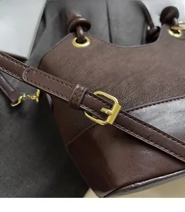 Detail view of brown leather bucket bag with adjustable strap and gold metal buckles