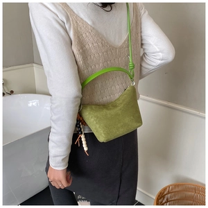 Detalle del bolso de ante verde con colgante de cuentas y dos correas de hombro