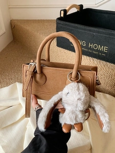 Brown rectangular crossbody bag with round handles and a cute grey rabbit charm
