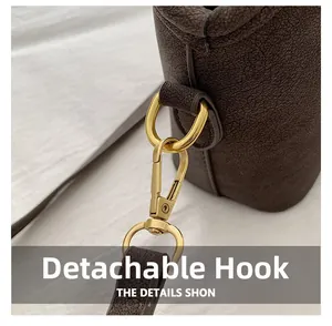 Macro view of detachable gold hook and dark brown litchi pattern leather bag detail