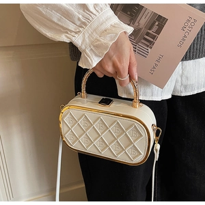 Close-up of quilted white crossbody bag with golden handle and letter B embroidery