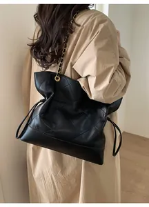 Detailed side view of large black quilted tote bag with gold chain and PAN TOR logo