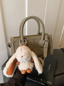 Olive green leather handbag with rabbit charm and adjustable shoulder strap