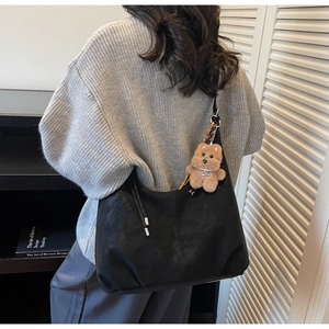Detail of minimalist black faux suede tote bag with a cute brown bear charm on the strap