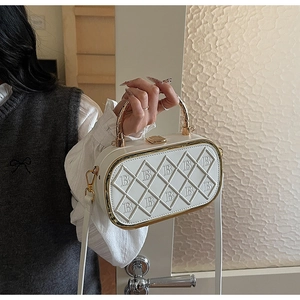 Close-up of white quilted leather crossbody bag with B embossing and gold handle