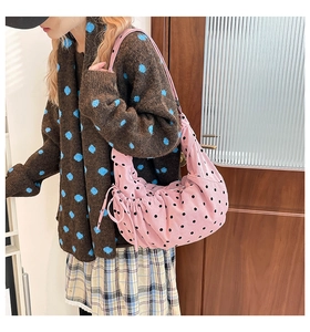 Détail du sac hobo rose en velours à pois avec cordon de serrage porté par un mannequin