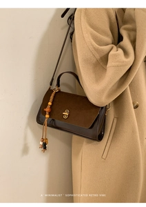 Close-up of retro leather shoulder bag with suede flap and beaded tassel on wool coat