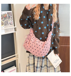 Sac bandoulière en velours côtelé rose à pois noirs avec cordon porté par un mannequin