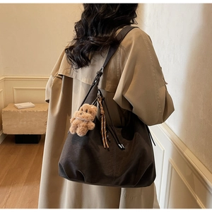 Detailed view of coffee brown suede tote bag featuring a cute plush bear and tassel charm