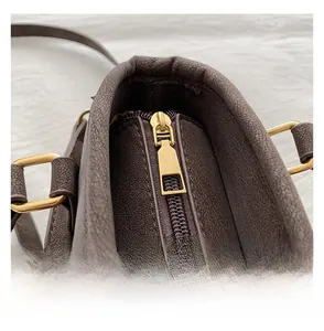 Detail view of smooth golden zipper and D-ring on dark brown leather tote bag