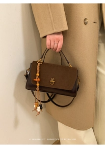 Detail of retro brown handbag with suede flap, golden lock and ethnic beaded tassel