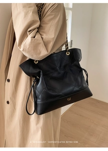 Close-up of black quilted tote bag with golden chain strap and side drawstring details