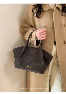 Detail view of vintage dark grey tote bag with gold metal plate and textured finish