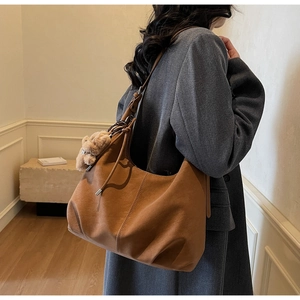 Brown suede tote bag side view on shoulder with plush bear charm and long strap